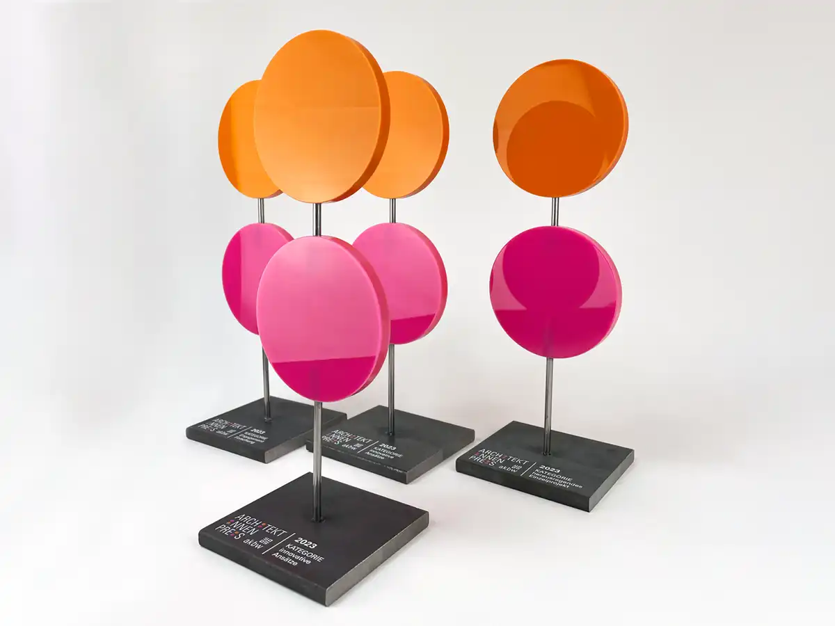 Award bestehend aus einer bedruckten Metall-Grundplatte und zwei farbigen (orange und Magenta) Acrylscheiben.