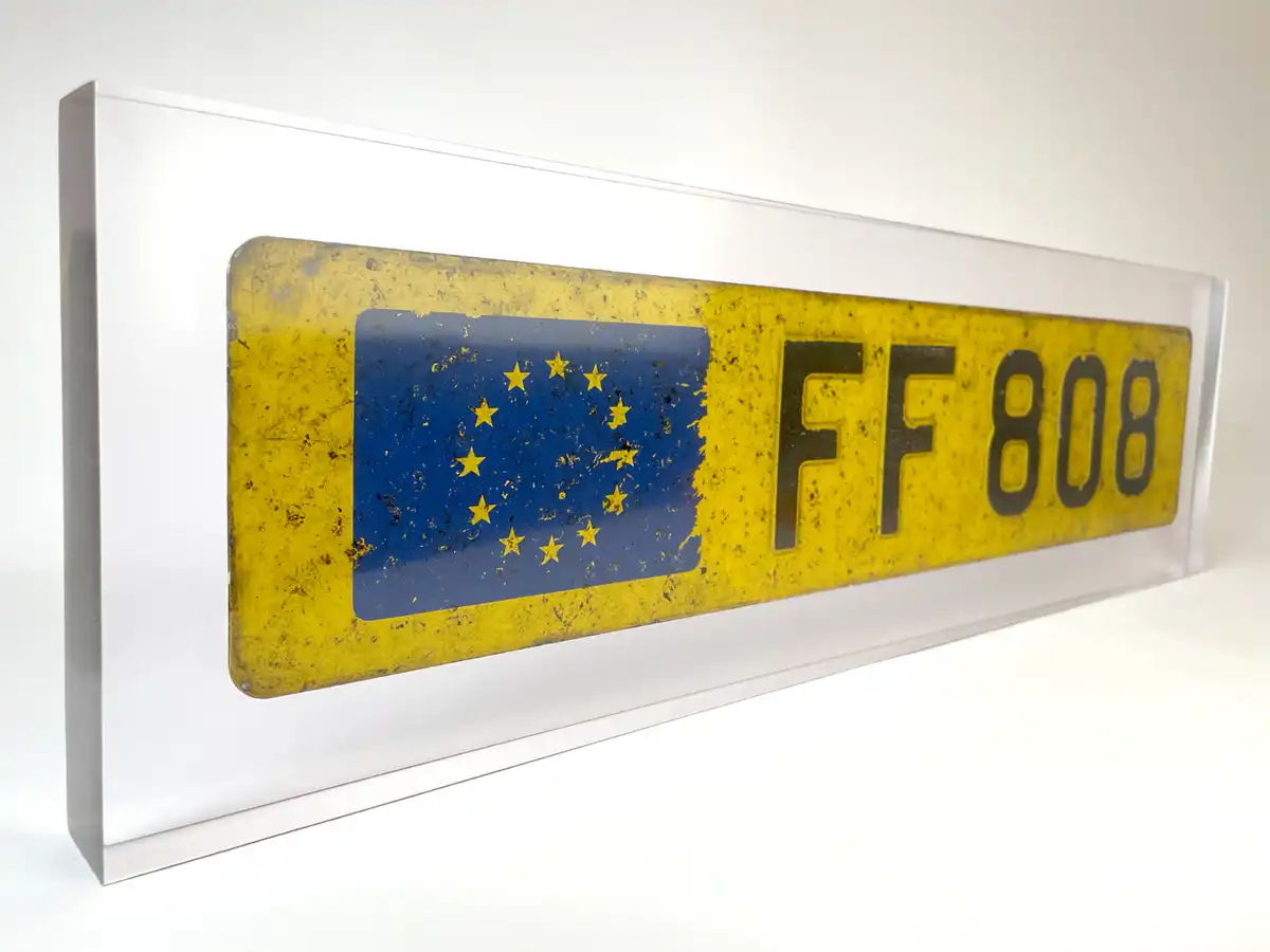 Gelbes Kennzeichen mit Europa-Fahne in einem Kunstharz-Block